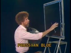 a man standing in front of a easel drawing on a board with the words russian blue