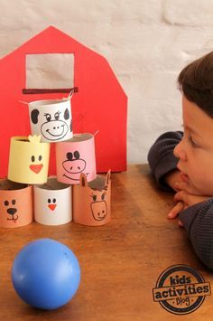 a little boy sitting at a table with some toilet paper rolls and a blue ball