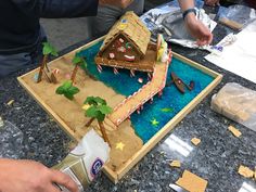 a gingerbread house made to look like it is on the table with people around