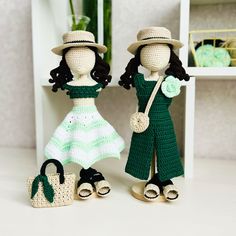 two crocheted dolls standing next to each other on a white table with green accents