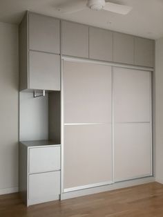 an empty room with white cupboards and drawers on the wall next to a ceiling fan