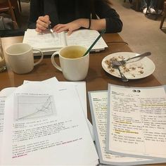 a woman sitting at a table with papers and coffee