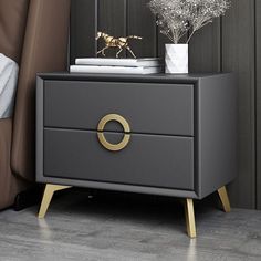 a black and gold bedside table with two drawers next to each other on top of a wooden floor