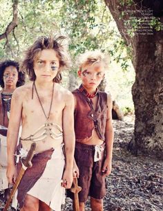 three young boys dressed up in native american clothing and holding axes, standing next to each other