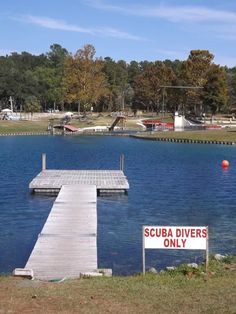 there is a sign that says scuba divers only on the dock next to the water