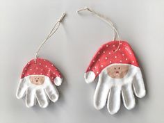 two white gloves with red and white santa claus hats hanging from the ends of them