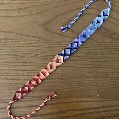 a blue and red bracelet on top of a wooden table next to an orange string