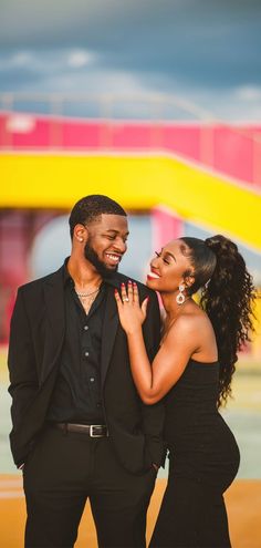 a man and woman standing next to each other in front of a colorful arch at an amusement park