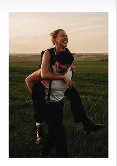 a man carrying a woman on his back in the middle of an open field with grass