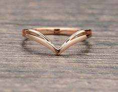 a gold ring with two wavy lines on the top and bottom, sitting on a wooden surface