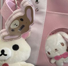 two stuffed animals are sitting next to each other in front of a pink bag with an animal keychain on it