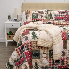 a bed covered in blankets and pillows with christmas decorations on the comforter, next to a night stand