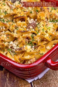 a red casserole dish filled with pasta and meat, topped with parmesan cheese