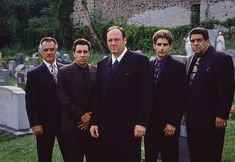 four men in suits and ties standing next to each other near headstones on gravestones