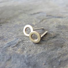 "These cute little organically shaped circles are hand crafted from solid 14k gold and your choice of sterling silver or solid 14k gold posts. Perfect for everyday wear, their understated matte finish adds just enough of a glimmer to complement any outfit. The tiny size also makes these perfect for second and third piercings. Priced per pair. Each 14k circle measures 5mm (~.1 inch) in diameter. Studs are mounted on either standard 20-gauge, nickel-free sterling silver or solid 14k yellow gold po 14k Gold Open Circle Earrings Gift, Dainty Circle Earrings In 14k Gold, Dainty 14k Gold Circle Earrings, Simple Yellow Gold Sterling Silver Earrings, Rose Gold Circle, Gold Circle, Circle Studs, Circle Earrings, Matte Gold