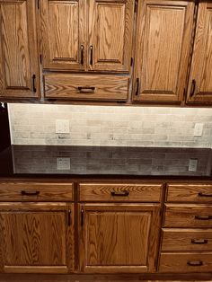 a kitchen with wooden cabinets and black granite counter tops in the center, along with white tiles on the backsplash