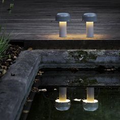 two lit candles sitting on top of a pond