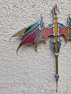 a stained glass bat hanging on the side of a building with an iron cross attached to it