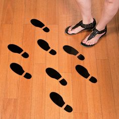 a person standing on top of a wooden floor next to black and white slippers