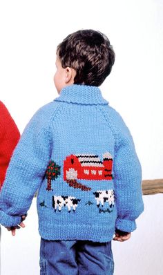 a little boy wearing a blue sweater with a red bus on it and another child standing next to him