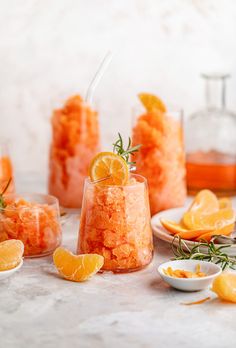 an assortment of oranges and other food items on a table with glasses, spoons and bottles