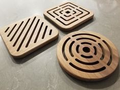 three wooden coasters sitting on top of a table next to each other with circles in them