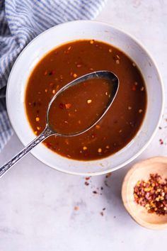 a white bowl filled with soup next to a wooden spoon on top of a table