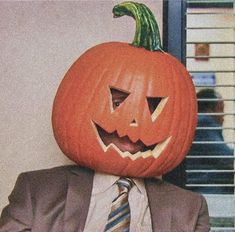 a man in a suit and tie with a pumpkin on his head