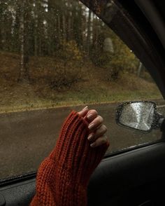 a person's hand in the passenger seat of a car with rain coming down