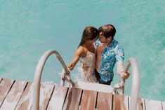 a man and woman standing on a dock next to the ocean