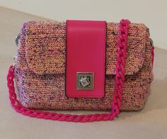 a pink and purple purse sitting on top of a white table next to a wall