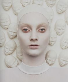 a white mannequin with many heads in front of it's face and eyes