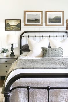 a bed with white linens and pillows in a small room next to two pictures on the wall