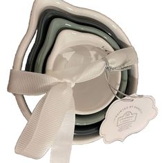 a stack of dishes with a white ribbon tied around it's edge and two empty plates in the middle