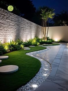 an outdoor garden at night with lights on the walls and grass in the foreground