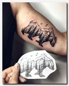 a man's arm with mountains and trees tattoo on the left side of his arm