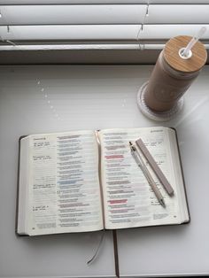 an open book sitting on top of a table next to a cup of coffee and a pen