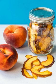 two peaches sitting next to a glass jar filled with gold coins and sliced peaches