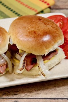 two sandwiches with bacon, cheese and tomato on a plate