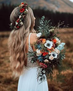 a woman with long blonde hair holding a bouquet in her hand and wearing a white dress