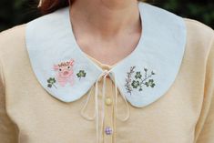 a close up of a woman wearing a collared shirt with embroidered animals on it