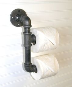 two rolls of toilet paper are hanging on the wall next to an old fashioned faucet