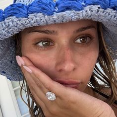 a woman wearing a blue and white hat with a diamond ring on her left hand