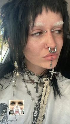 a woman with black hair and piercings on her nose is wearing chains around her neck