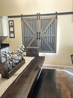 a table with vases on it in front of an open barn door that leads to the kitchen