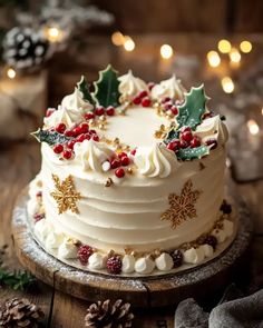 a white frosted cake decorated with holly berries and pine cones on a wooden table