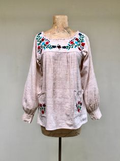 "* Exceptional Mexican peasant smock top c 1960s * Rustic woven lightweight cotton in a natural oatmeal color with brown highlights and slubs * Floral embroidery on yoke and patch pockets * Open neckline features a tuck-pleated border * Long, full, set-in sleeves are gathered into sewn cuff * Squared-off hem with 4\" slide slits * Goes on over head No label Excellent condition Bust: 34 Hip: 42 Shoulder: 15 1/2 Sleeve: 21 1/2 Length: 25 Garments are flat-measured. Please compare these measurement Folk Style Peasant Tunic Top With Floral Embroidery, Folk Style Peasant Top With Floral Embroidery, Spring Peasant Top With Yoke, Spring Peasant Top With Yoke Detail, Peasant Style Embroidered Tunic Top, Long Sleeve Smocked Peasant Top, Bohemian Cotton Peasant Top With Smock Details, Bohemian Cotton Smock Peasant Top, Smock Top