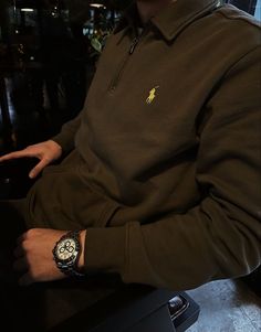 a man sitting at a table with a watch on his left hand and wearing a polo shirt