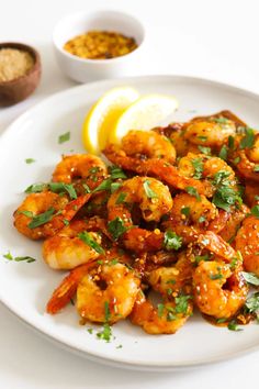 a white plate topped with shrimp next to a lemon wedge and garnished with parsley