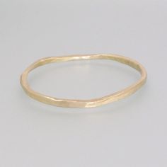 This simple bangle made of brass captivates with its simple, rustic, yet appealing form. The piece was hand-forged and then poured off into a mold. It was then hammered to create its irregular and unique appearance, with each copy having a subtly different look. This bangle is a great accessory for everyday wear and can also be a successful complement to our various casting rings. Dimensions: Size: approx. 7.87 inch, 20 cm  Width: 0.08-0.16 inch, 2-4 mm  Thickness: 0.08-0.16 inch, 2-4 mm Handmade Minimalist Brass Bangle, Minimalist Handmade Brass Bangle, Minimalist Hand Forged Brass Bracelets, Hammered Yellow Gold Brass Bangle, Minimalist Hand Forged Gold Bangle, Gold Minimalist Hand Forged Bangle, Rustic Hammered Gold Jewelry, Simple Bangle, Brass Bangle